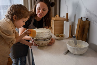 Mother and son baking carrot cake together at cozy kitchen. home cooking, family life
