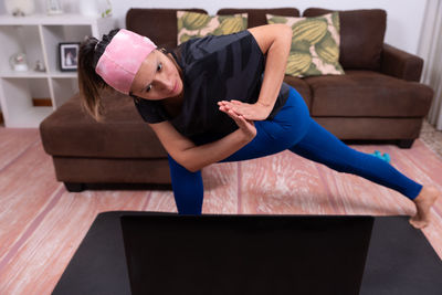 Low section of woman sitting on sofa at home