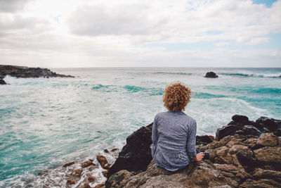 Rear view of woman looking at sea against sky