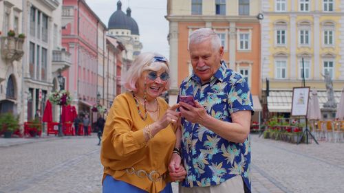 Smiling couple using mobile phone in city