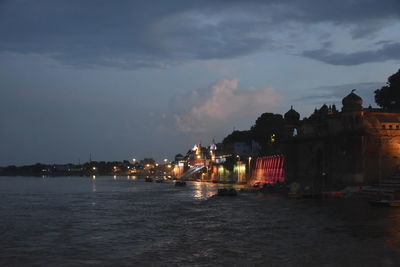 Buildings by sea against sky at night