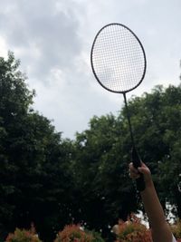 Man holding racket against trees