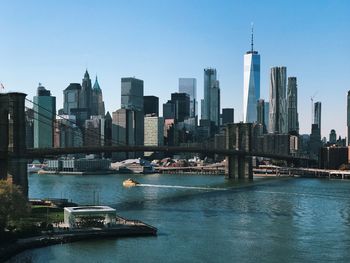 Brooklyn bridge and east river against sky in city