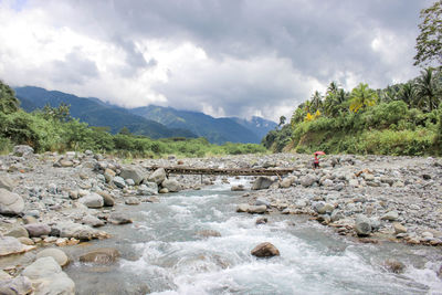 Scenic view of river by mountains against sky