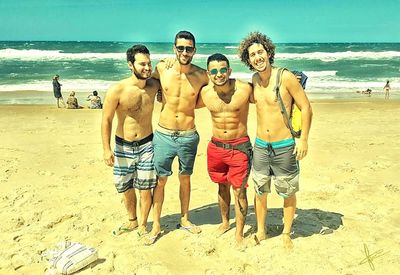 Rear view of friends standing on beach