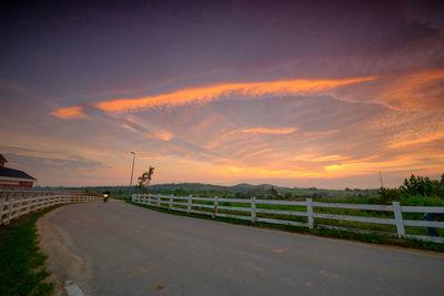 Empty road against sky during sunset