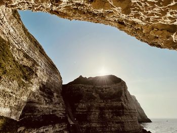 Rock formations by sea against clear sky