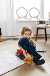 Girl wearing pant to doll on floor at home