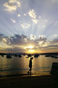Silhouette man standing on beach against sky during sunset