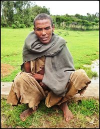 Portrait of man sitting on grassy field