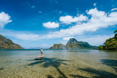 Man on raft in sea against sky