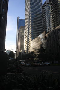 Cars on street by buildings against sky in city