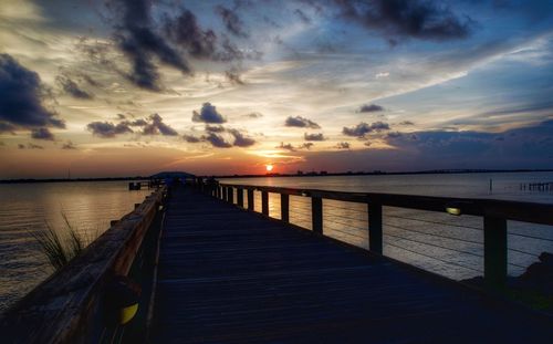 Pier over sea against sky during sunset