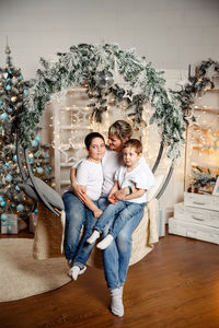 Happy children with mom sits in front of the christmas tree
