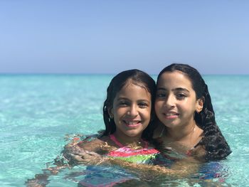 Two girls portrait in crystal clear water sea and clear blue sky