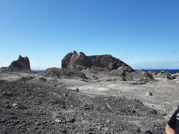 Rock formations on landscape against clear blue sky