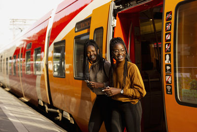 Smiling female friends leaving train