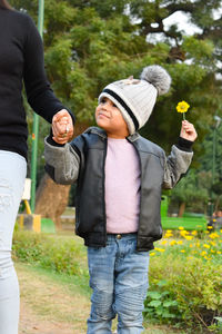 Midsection of woman holding son hand while walking in park