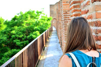 Rear view portrait of woman against brick wall