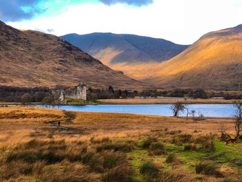 Scenic view of lake by mountains against sky