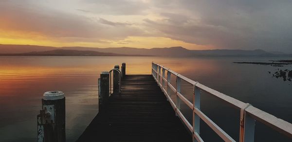 Pier over lake against sky during sunset