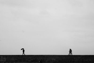 Silhouette people riding bicycle on field against sky