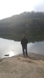 Man standing by lake against sky