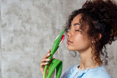 Portrait of woman holding face against wall