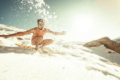 Low angle view of man splashing water at beach against sky
