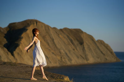 Woman standing by sea against clear sky