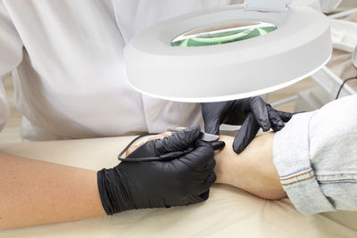 Cropped electrologist remove hair on woman's toes, foot with hair removal electrolysis procedure