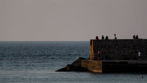 Mediterranean landscape of sicily with sea water, boats, dike and some rocks.