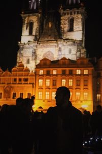 Silhouette people standing against illuminated building at night