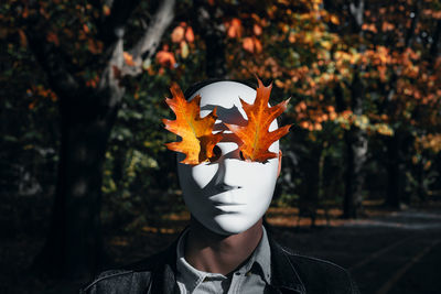 Portrait of person holding orange leaf during autumn