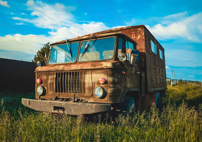 Abandoned truck on field against sky