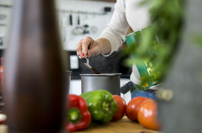 Cropped image of senior woman preparing coffee in kitchen