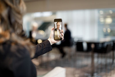 Mid adult professional discussing through video conference on smart phone at workplace