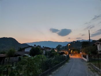 Street amidst buildings against sky during sunset