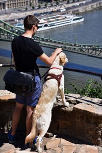 Rear view of man with dog standing by sea