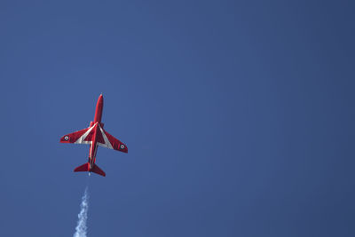 Low angle view of airplane flying against clear blue sky