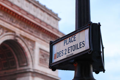 Low angle view of sign against sky in city