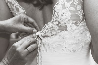 Cropped hands of bridesmaid adjusting bride dress