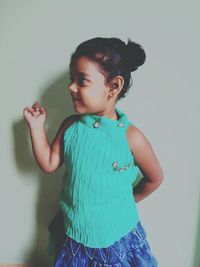 Girl looking away while standing by wall