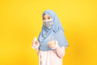 Portrait of a teenage girl against yellow background