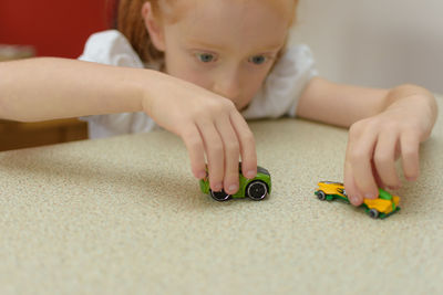 Close-up of girl playing with toy cars on table