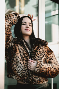 Young woman with eyes closed standing against wall