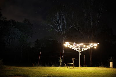 Illuminated clotheslines on grassy field at night