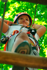 Cute boy sitting on zip line in forest