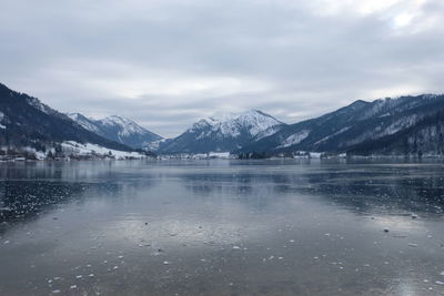 Scenic view of lake by snowcapped mountains against sky