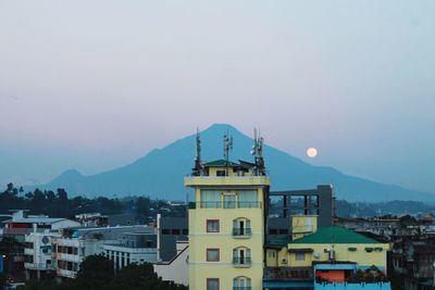 View of town with mountain in background at dusk